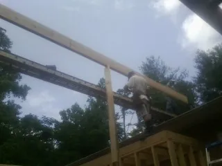 Carpenter setting a ridge beam over a new addition frame — Ice Dam Removal by Roofing Brothers in Moncks Corner