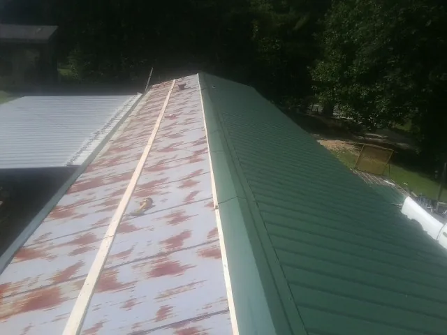 Old rusted panels beside newly installed green metal roofing — Wind Damage Roof Repair by Roofing Brothers in Moncks Corner