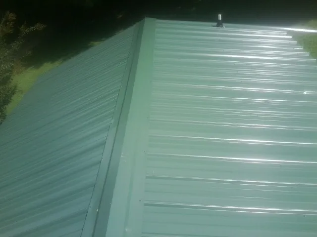 New green metal panels meeting at the ridge of a roof — Flat Roof Repair work by our crew in Moncks Corner