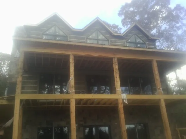 Dormers and porch framing on a large log home under construction — Roof Coating work by our crew in Moncks Corner