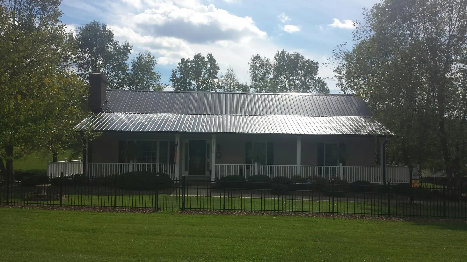 Gray metal roof on a brick ranch with a full width front porch — Gutter Guard Installation work by our crew in Moncks Corner