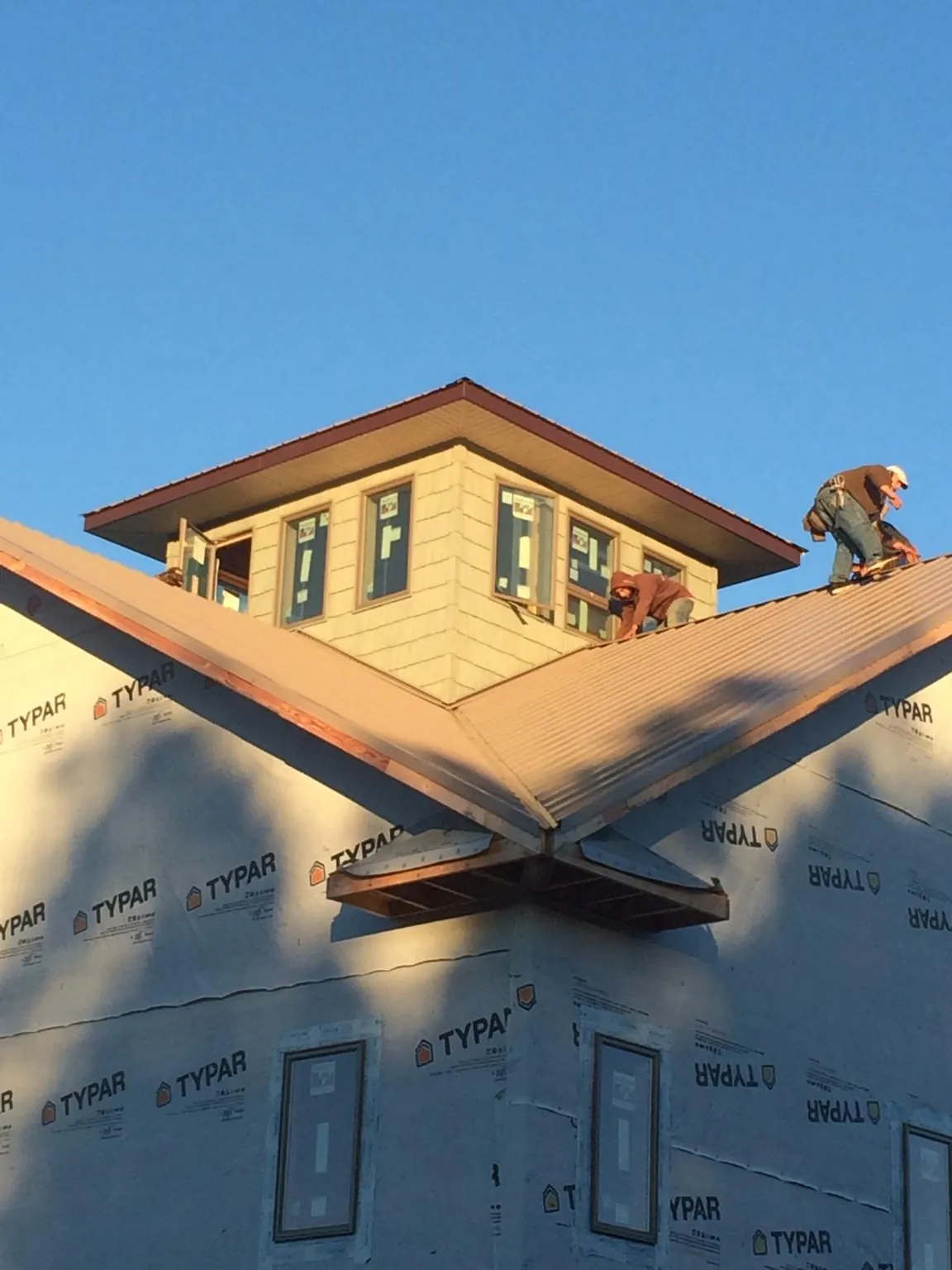 Roofers working around a rooftop cupola on a new metal roof at sunset — Roof Waterproofing in Moncks Corner by Roofing Brothers